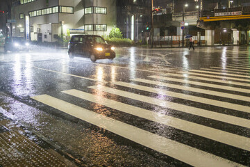 Small car crosses intersection in heavy rain at night