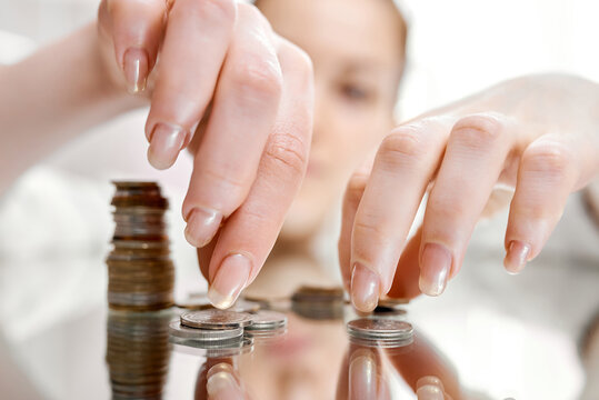 Woman collects stack of coins scattered on mirror table