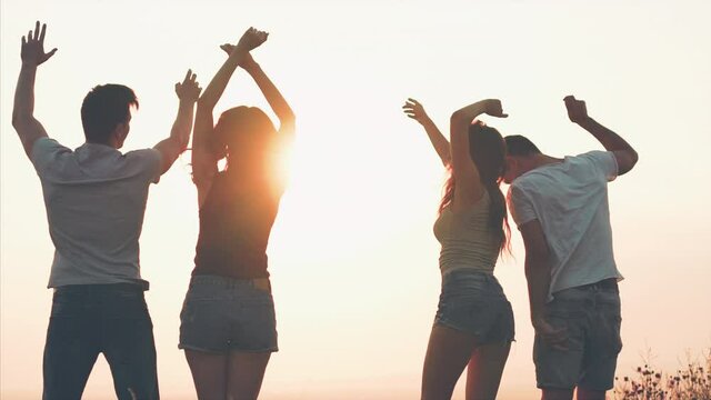 The four friends dancing on the sunrise background. slow motion