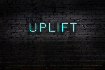 Neon sign. Word uplift against brick wall. Night view