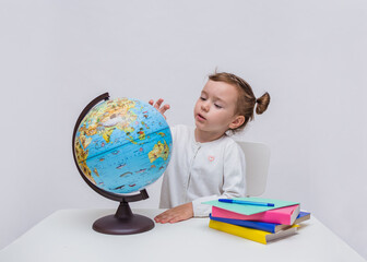 A young pupil studies a globe on a white isolated background with space for text
