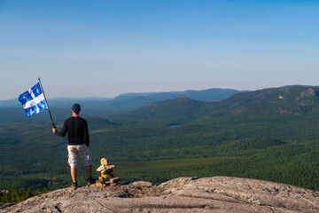 Man with a fleurdelisé flag from Quebec on the top of "La Chouenne" mountain in Charlevoix