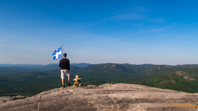 Man with a fleurdelisé flag from Quebec on the top of "La Chouenne" mountain in Charlevoix
