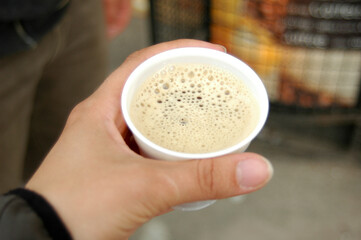 Paper cup of coffee from coffee machine in female hand in a city