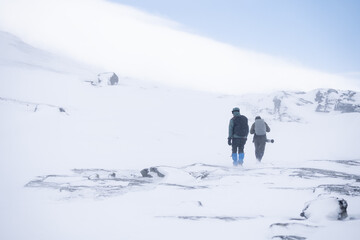 Naklejka na ściany i meble Hikers and photographer in the dovrefjell national park, Norway. Man hiking in winter 