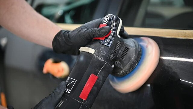 Slow motion closeup footage of professional hands polish a car door.