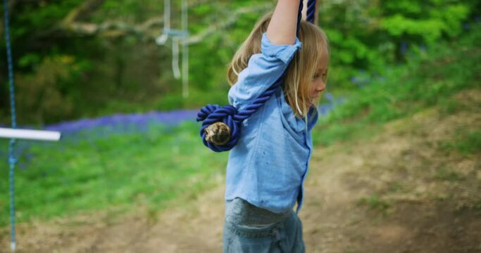 Preschooler boy playing on rope swing in nature