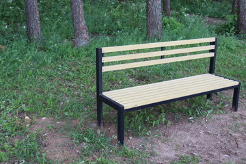 yellow bench with trash can in forest