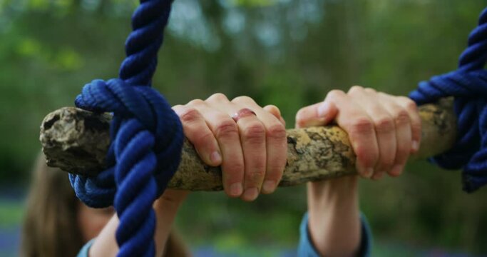 The hands of a young woman holding a rope swing