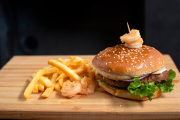 Homemade burger with french fries on a wooden board - barbecue at home - cooking meat on the grill