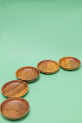 Obraz na płótnie Canvas 緑の背景に置いた丸い木製の皿
