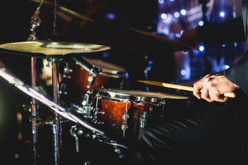 View of drum set kit on a stage during jazz rock show performance, with band performing in the background, drummer point of view