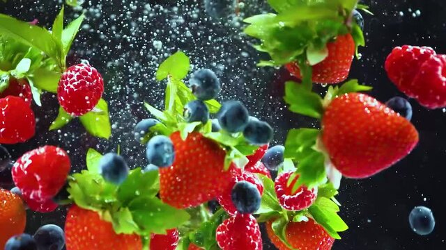 Strawberries, blueberries, raspberries, mint splash in the water, close-up