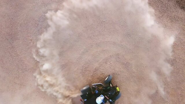 Riding quad bike. Man in protective equipment and helmet, drifting on his ATV. Slow motion aerial footage. High quality FullHD footage