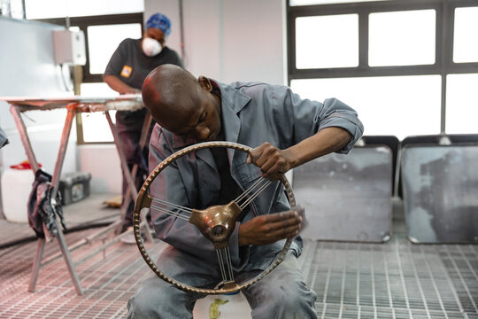 African American mechanic inspecting a steering wheel