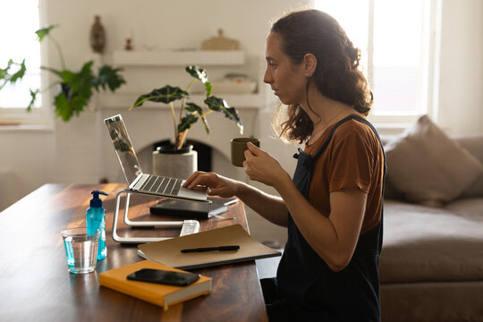 Woman with coffee cup using laptop at home