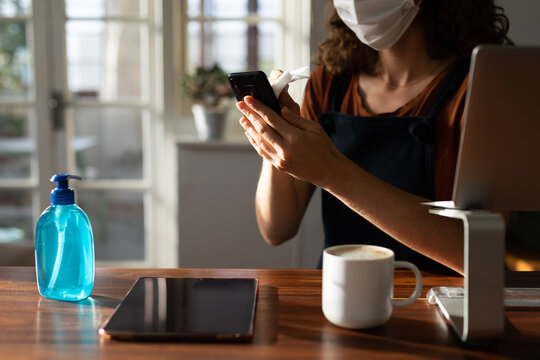 Mid section of woman wearing face mask cleaning her smartphone