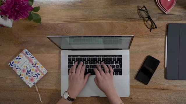 Hands typing her work on a laptop
