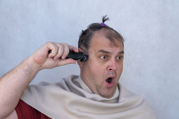 man cuts his own hair on his head. cutting hair with a clipper. beauty salons do not work due to quarantine, self-isolation mode