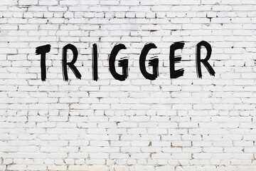 Inscription trigger painted on white brick wall
