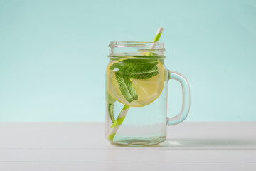 Cold water with lemon and mint in a glass Cup on a white table.