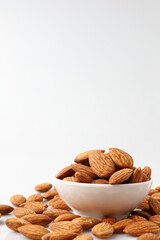 Almonds nuts in white bowl isolated on a white background with copy space is useful to help neutralize free radicals, help prevent Alzheimer's disease, helping repair the wear and tear on the body.