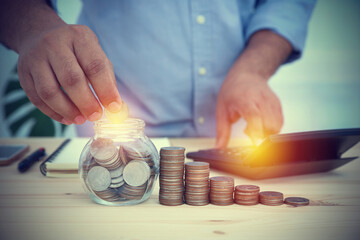 The businessman is picking up a coin in a glass jar to save in the future. Concept business,...