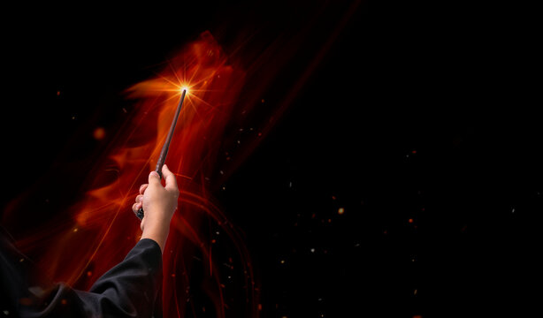 Hand holding Magic wand in the flames, Miracle magical stick Wizard tool on hot fire.