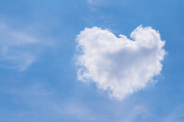 Naklejka na ściany i meble White fluffy cloud in heart shape on blue sky.
