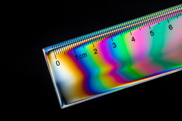 close up of a ruler in polarized light on black background.