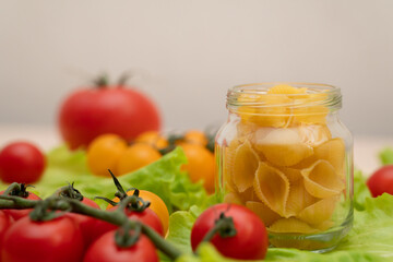 Pasta with vegetables in a plate.  Ingredients for cooking Italian Pasta. Tomatoes, cherry greens. Background from spaghetti.
