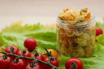 Pasta with vegetables in a plate.  Ingredients for cooking Italian Pasta. Tomatoes, cherry greens. Background from spaghetti.