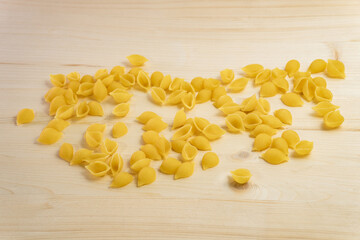 Macaroni is scattered on the table. Ingredients for the preparation of Italian pasta tomatoes, cherry greens. Background from spaghetti.