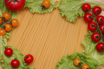 Background from spaghetti. Frame for the recipe of products. View from above. Ingredients for Italian pasta tomatoes, cherry greens.