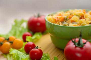 Pasta with vegetables in a plate.  Ingredients for cooking Italian Pasta. Tomatoes, cherry greens. Background from spaghetti.