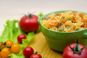 Pasta with vegetables in a plate.  Ingredients for cooking Italian Pasta. Tomatoes, cherry greens. Background from spaghetti.