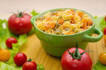 Pasta with vegetables in a plate.  Ingredients for cooking Italian Pasta. Tomatoes, cherry greens. Background from spaghetti.