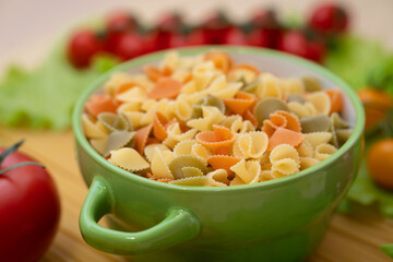 Pasta with vegetables in a plate.  Ingredients for cooking Italian Pasta. Tomatoes, cherry greens. Background from spaghetti.