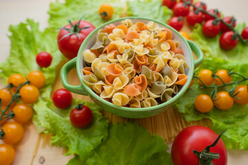 Pasta with vegetables in a plate.  Ingredients for cooking Italian Pasta. Tomatoes, cherry greens. Background from spaghetti.