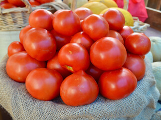 Fototapeta na wymiar A beautiful arrangement of red ripe beefsteak tomatoes for sale at a local farmstand. Closeup.