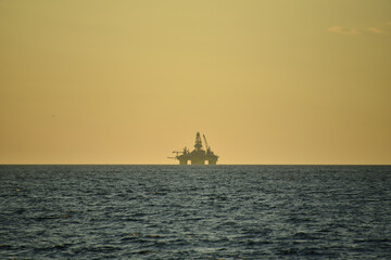Obraz premium Drilling platform at sea. Extraction of minerals on the shelf. A huge red platform rises above the water. Storm at sea. Hydrocarbon energy. 