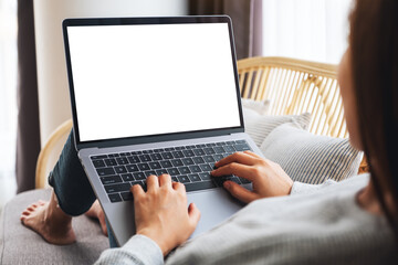 Mockup image of a woman working and typing on laptop computer with blank screen while sitting on a sofa at home - Powered by Adobe