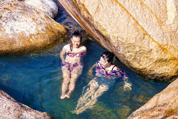 Fototapeta premium In summer, two girls soak in the mountain spring between the streams