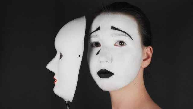 Theatrical cosmetics sad mask. The girl hides emotions behind a mask.
