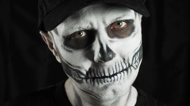 Makeup skeleton for Halloween. Human skeleton on a dark background. A man is looking at the camera.
