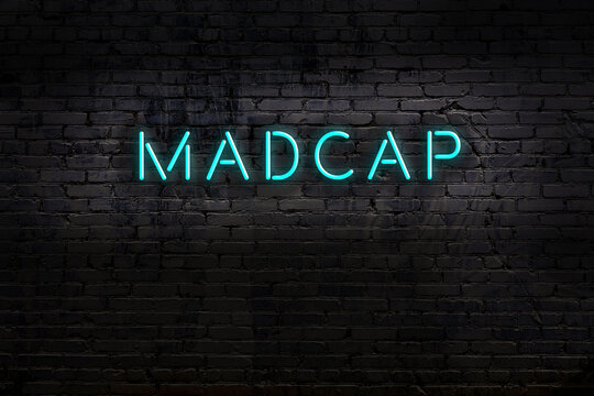 Neon sign. Word madcap against brick wall. Night view