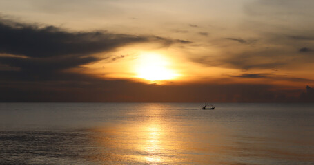 silhouette boat in the sea at sunset on the beach