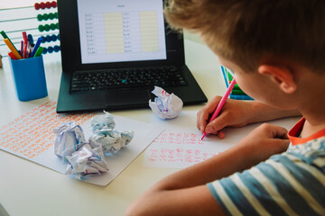 Kid doing her homework with laptop at home. Education and distance learning for kids.