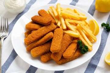 Homemade Fish Sticks and French Fries with Tartar Sauce on a white wooden table, low angle view. Close-up.