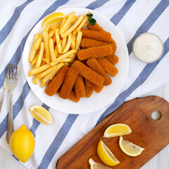 Homemade Fish Sticks and Fries with Tartar Sauce on a white wooden table, top view. Flat lay, overhead, from above.